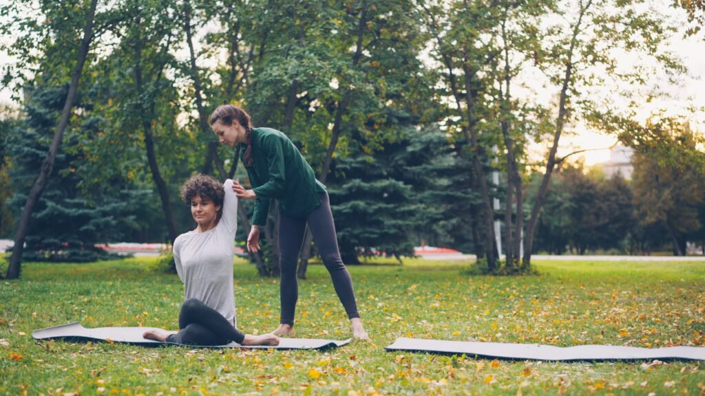Two women practicing yoga in a park