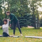 Two women practicing yoga in a park